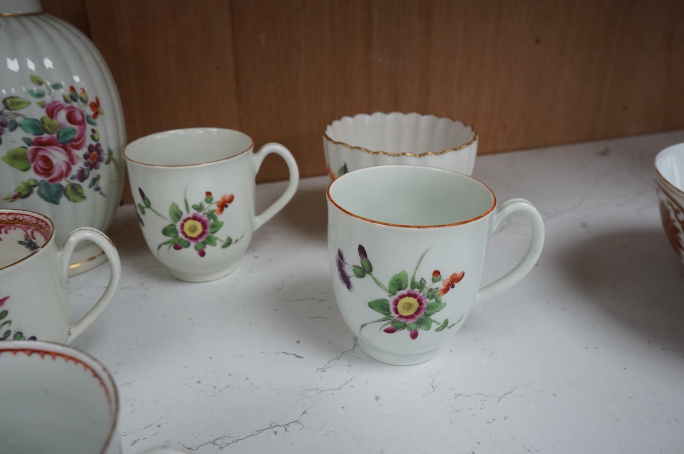 Worcester polychrome tea and coffee wares, c.1760-1780, comprising a tea caddy, a cream jug, five coffee cups and a fluted bowl, the latter with red anchor mark (8), largest tea caddy 14cm high.